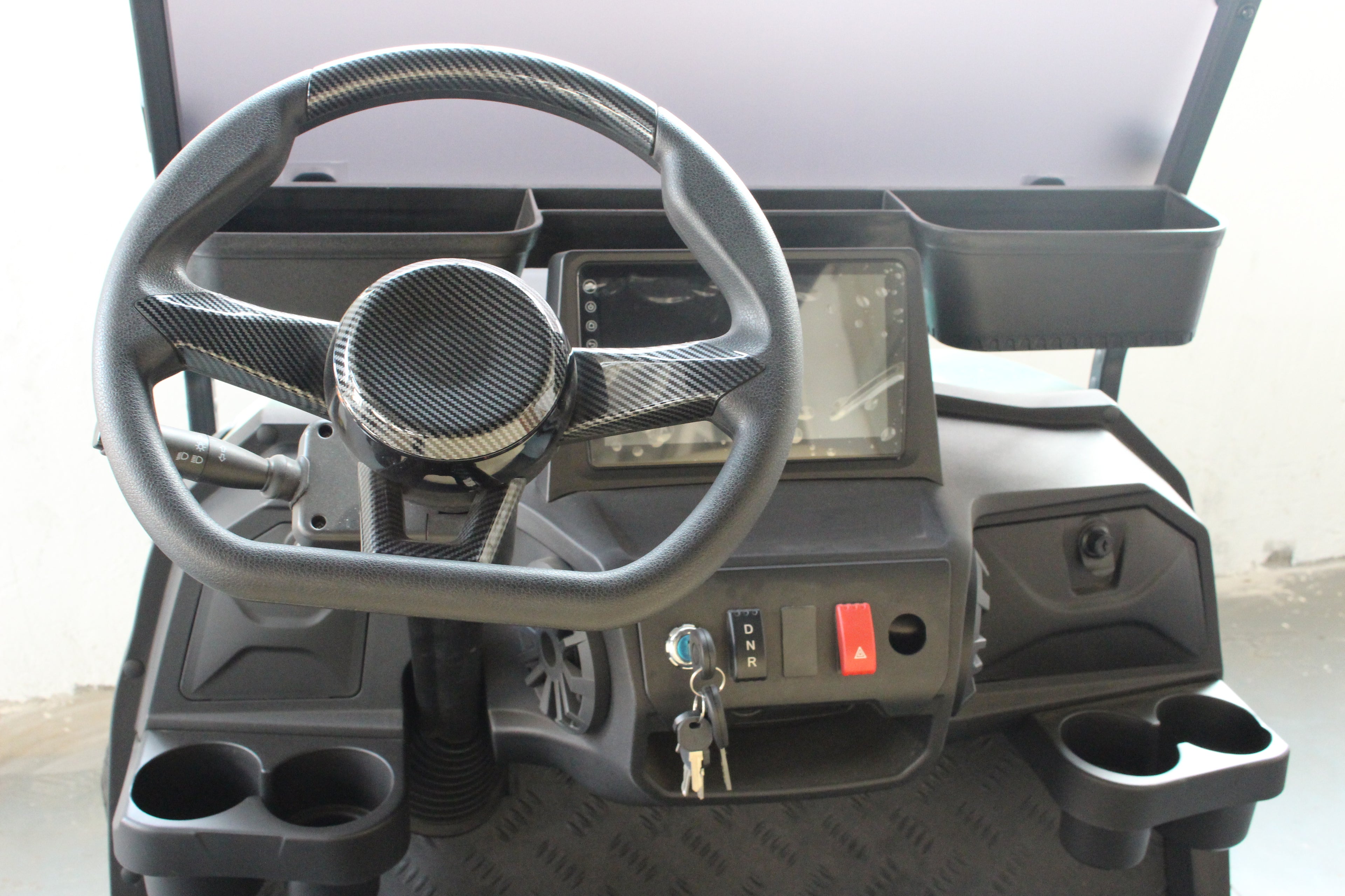 Steering wheel and dashboard of a electric golf cart with cup holders and controls.