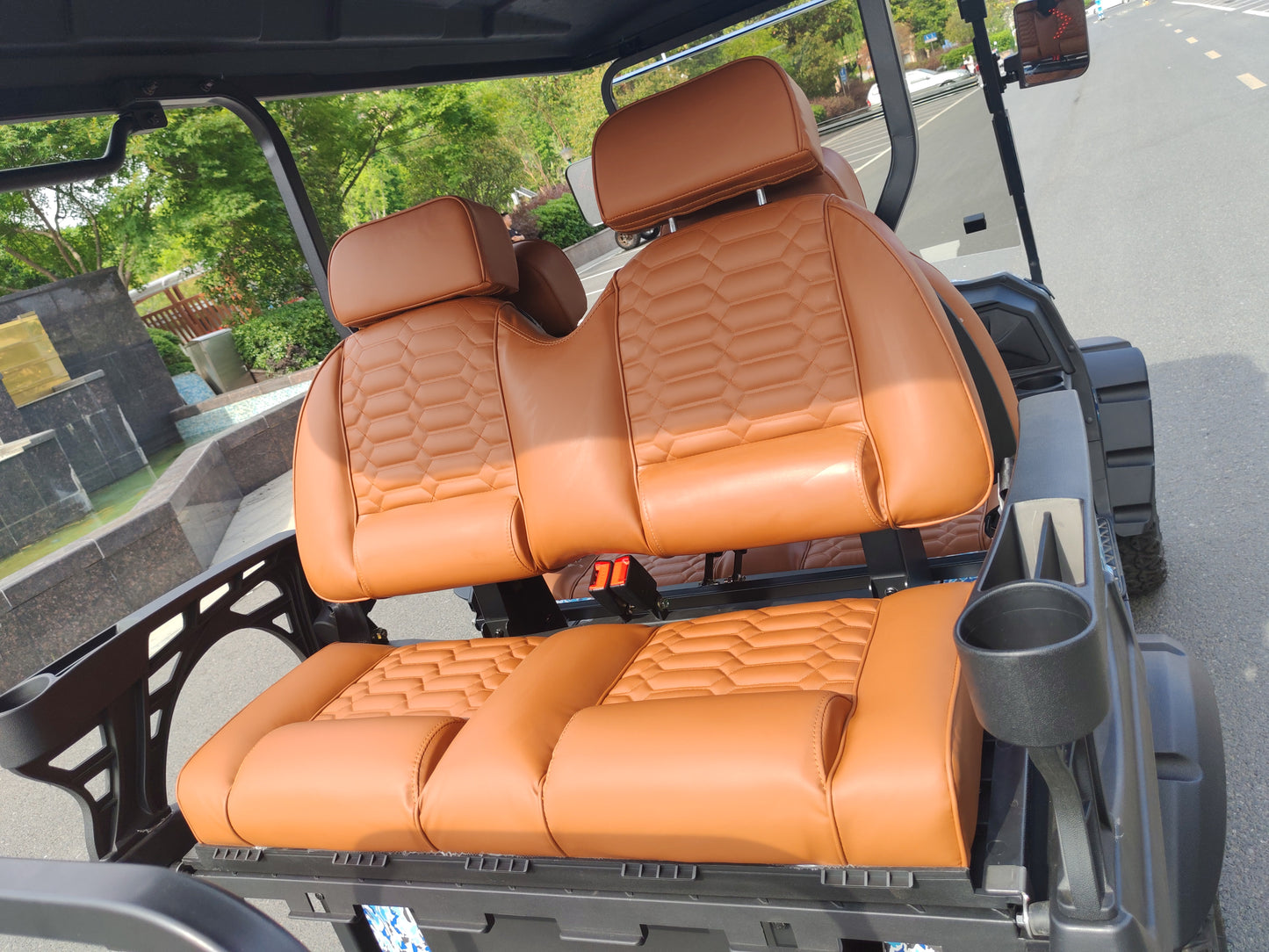 Brown leather seats inside a golf cart with a blurred outdoor background